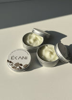Two open tins of Ekani cream on a light surface with a neutral background grass-fed beef tallow face cream in tin jar